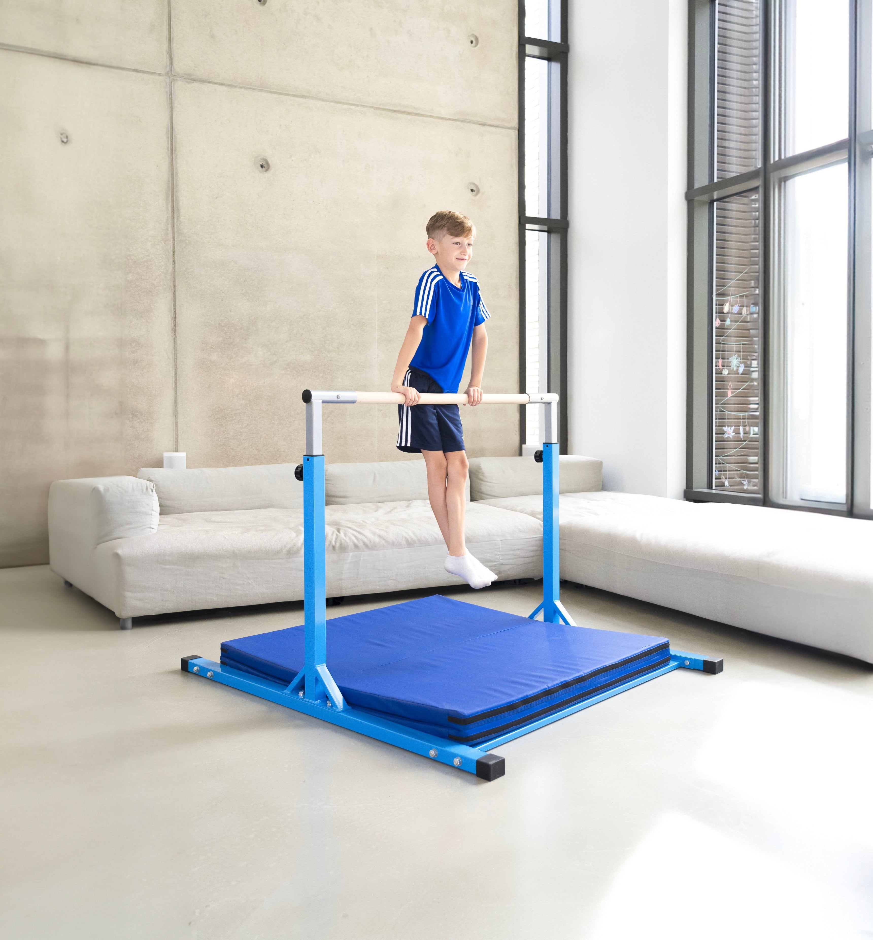 Junge turnt an einem blauen Turnreck mit Matte im Wohnzimmer. Das Turnreck steht stabil auf dem Boden und bietet Kindern die Möglichkeit, drinnen sicher zu trainieren und Spaß zu haben.
